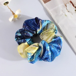 Detailed view of Van Gogh starry night oil painting print satin scrunchie on a white desk