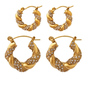 U-shaped twisted rope gold earrings with shimmering cubic zirconia stones on white background