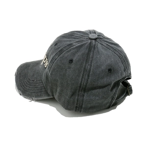 Close-up of distressed vintage grey baseball cap showing frayed brim and metal buckle