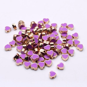 Macro detail of purple enamel heart beads with gold-plated alloy for DIY jewelry