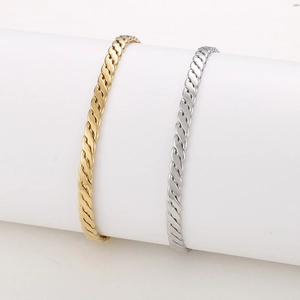 Détails de bracelets joncs torsadés or et argent sur des supports cylindriques blancs