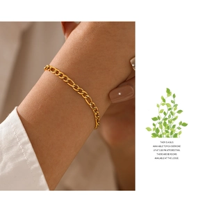 Detail view of a gold-plated stainless steel Figaro chain bracelet worn on a wrist