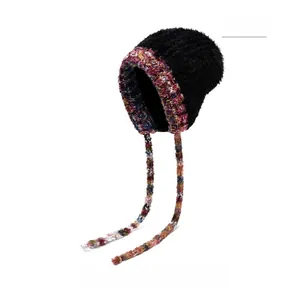 Détail d'un bonnet d'hiver en fausse fourrure noire avec glands ethniques colorés