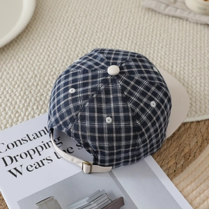 Detail of navy checkered kid's cap featuring floral embroidery and adjustable back strap