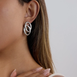 Gros plan de boucles d'oreilles ovales en acier inoxydable argenté portées par un mannequin