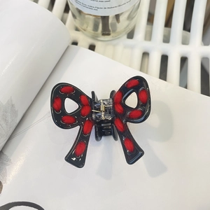 Détail du bord tissé en fil rouge sur une pince à cheveux nœud noir au style rétro