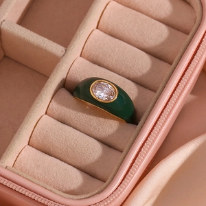 Detail of emerald enamel ring with oval gemstone in pink velvet jewelry box