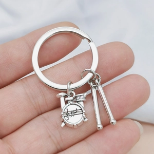 Detailed view of silver drum kit and drumsticks pendants on a music themed keychain