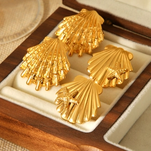 Macro shot of gold shell and starfish earrings displayed in a premium wooden jewelry box