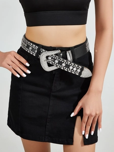 Vue détaillée d'une ceinture punk à strass et rivets portée sur une jupe en jean noire
