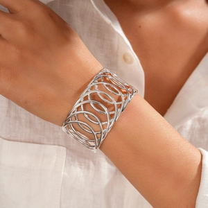 Détail du bracelet ajouré argenté porté sur la manche d'une chemise en lin