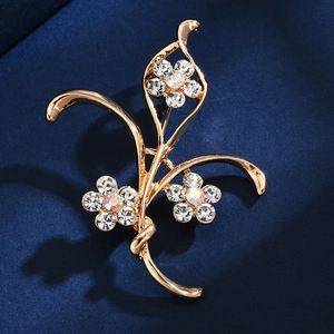 Golden floral brooch with crystals on dark blue velvet, showing elegant craft detail