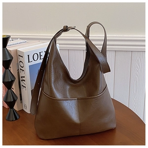 Détail macro d'un sac hobo marron foncé avec texture cuir vintage et large bandoulière