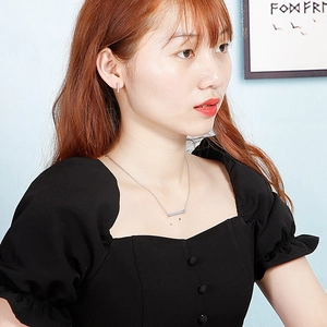 Silver minimalist bar necklace and stud earrings set worn by a female model on black top