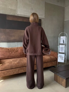 Rear view of brown half-zip sweatshirt and wide-leg sweatpants set in industrial setting