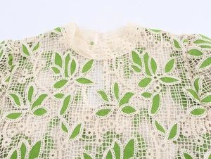 Détail du col rond et de la dentelle au crochet aux motifs de feuilles vertes sur beige