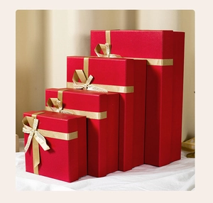Detailed view of red gift boxes in four sizes with elegant gold ribbons and bows