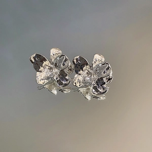 Detailed view of silver irregular pleated floral earrings with metallic textured finish