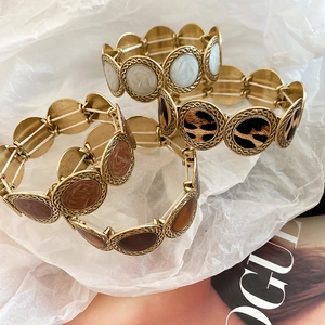 Detail of leopard print and marble pattern resin inserts on gold elastic bracelets