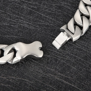 Macro detail of silver matte Cuban link chain with unique bone-shaped buckle and safety clasp
