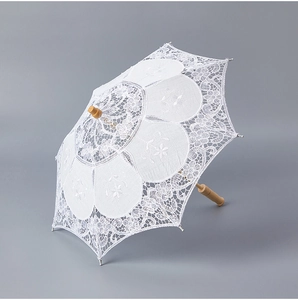 Close-up of intricate white lace embroidery and vintage wooden handle of the wedding umbrella