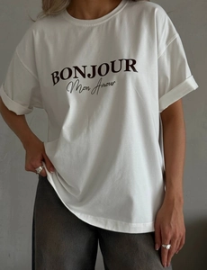 Détail de l'inscription artistique noire 'BONJOUR Mon Amour' sur un T-shirt blanc en coton