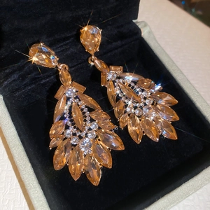 Détails des boucles d'oreilles gouttes avec cristaux ambrés sur velours noir chic