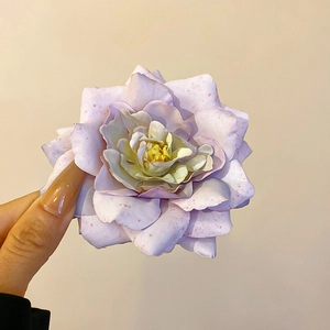 Detailed close-up of a purple spotted fabric rose hair clip with a soft yellow center