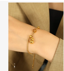 Macro view of gold stainless steel bracelet with gourd charm and Fu character bead