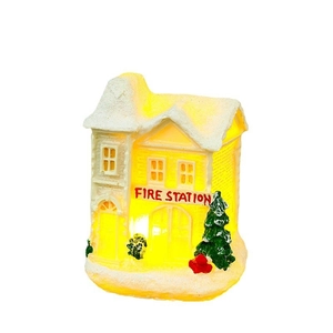 Lighted Christmas resin fire station decor with warm LED glow on white background