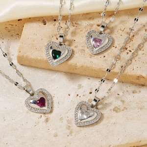 Elegant heart-shaped zircon necklace in four colors displayed on a beige stone and silk