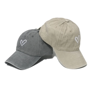 Détail de la broderie cœur sur casquettes en coton lavé en gris foncé et kaki