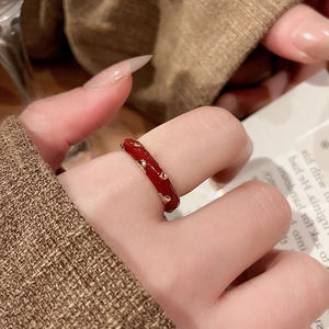 Detail of red enamel gold-plated ring with heart motif worn on a finger
