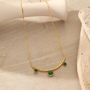 Dettaglio della collana in acciaio inossidabile dorato con tre perline in pietra verde
