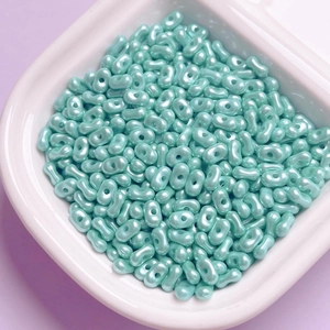 Detailed view of light blue pearlized acrylic peanut beads in a ceramic tray