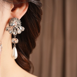 Close-up of floral crystal earrings with teardrop pearls worn by a model