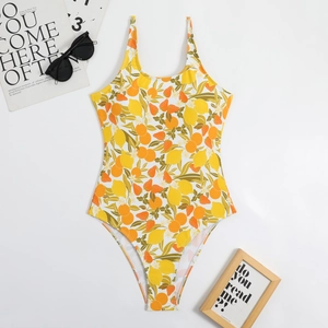 Flat lay of yellow one-piece swimsuit with fruit print and summer fashion accessories