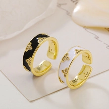 Macro detail of gold adjustable open rings with black and white enamel and crystal inlay