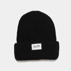 Detail shot of black knitted beanie with AQER woven patch and premium ribbed texture
