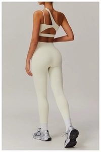 Détail du soutien-gorge de sport à une épaule blanc cassé et du pantalon de yoga taille haute