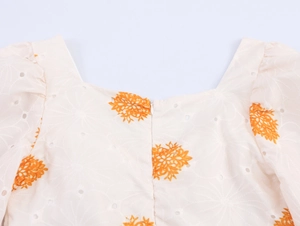 Detalle de bordado floral y textura calada en la espalda del vestido con cuello cuadrado