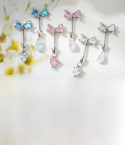 Detail of silver bow and heart pendant body jewelry with blue and pink zircon stones