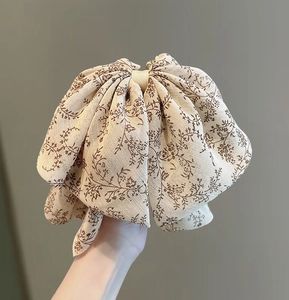 Gros plan sur une pince à cheveux nœud en mousseline fleurie beige crème et marron