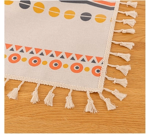Close-up of Bohemian linen tablecloth featuring orange geometric patterns and tassel edges