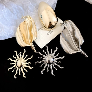 Detailed close-up of gold and silver sun and leaf brooches with textured metallic finish