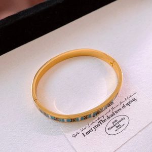 Détail d'un bracelet en acier titane doré avec motifs géométriques en émail