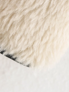Close-up of soft off-white faux fur texture on the collar of a plush winter jacket