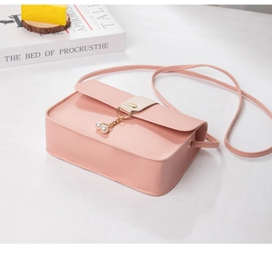 Detail of pink PU leather crossbody bag featuring pearl charm and metal ring closure
