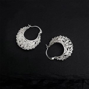 Close-up of ethnic hollow pattern design on silver metallic hoop earrings texture