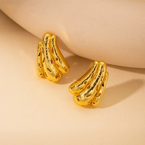 Macro detail of irregular gold earrings with unique hollow circular pattern and texture